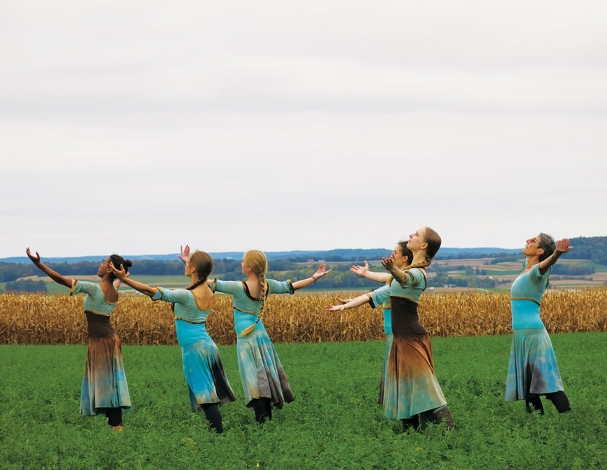 Women standing in field with arms up in the air