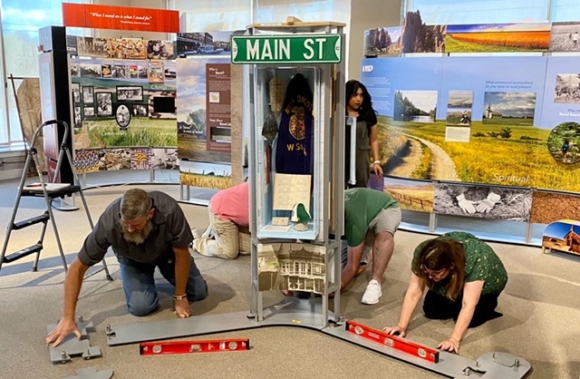 Three people installing exhibit