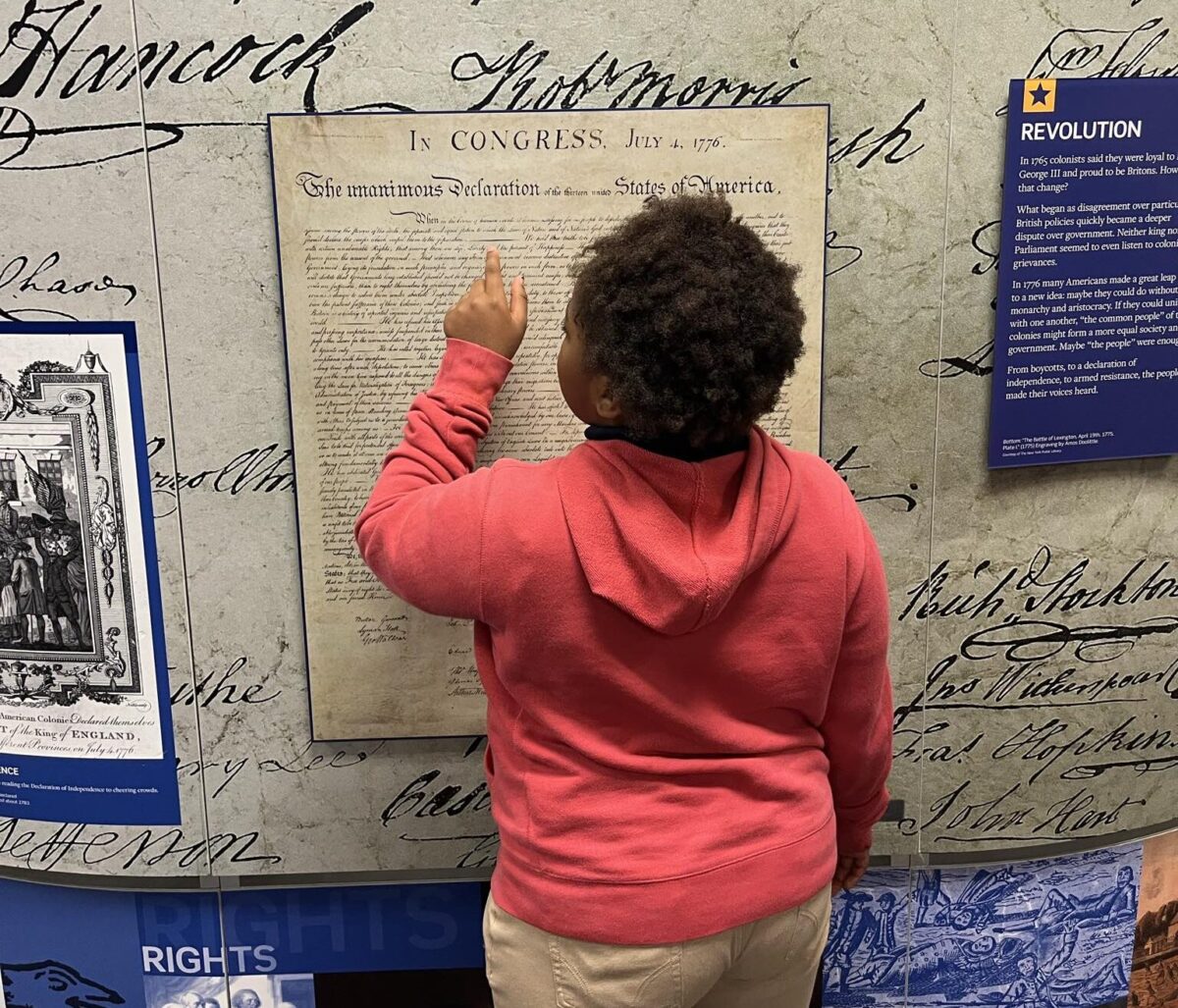 Child Stands in front of Voices and Votes exhibtiion
