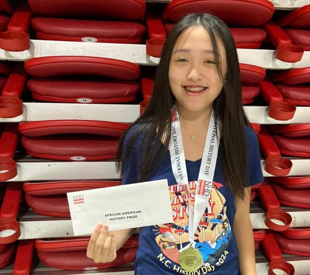 Hong stands with medal around her neck and an envelope in her hand