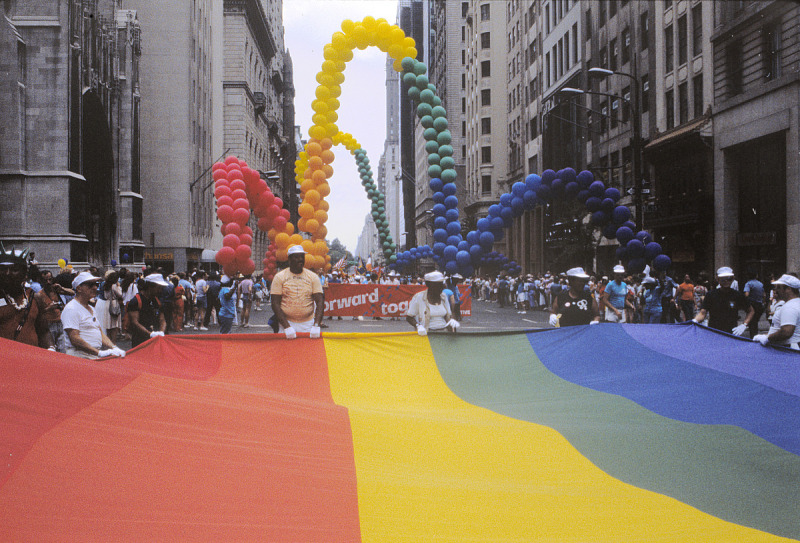 A color photographic slide depicting a large gay pride banner flag at a gay rights parade in New York City.